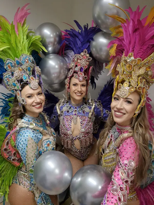 Trzy tancerki samby wśród balonów na przyjęciu urodzinowym