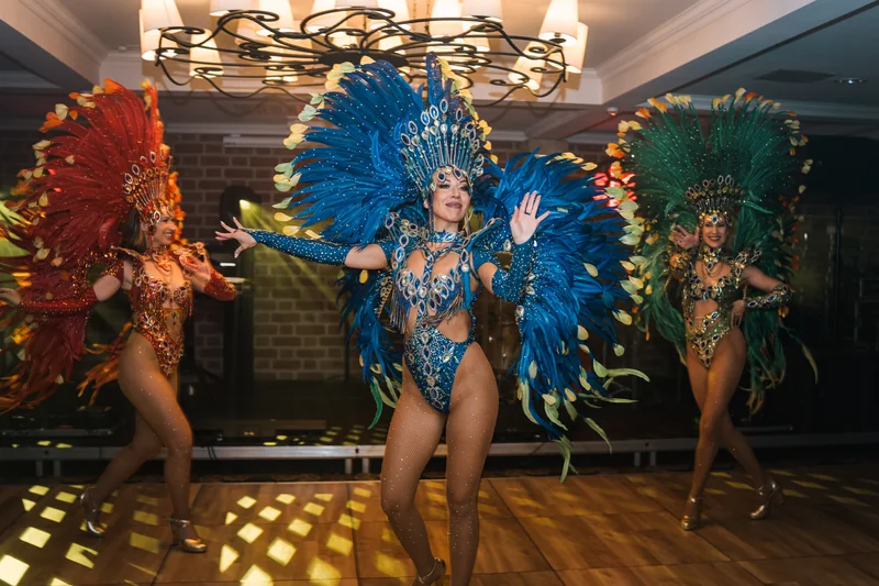 Samba karnawałowa: trzy tancerki w czerwonych, niebieskich i zielonych pióropuszach